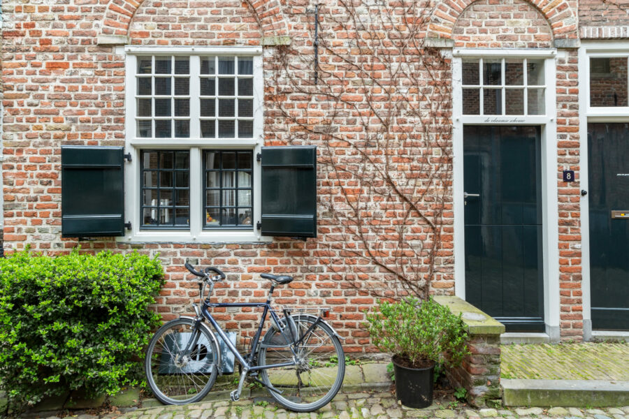A Bike parked in Front of a Brick Building with Black Shuttered